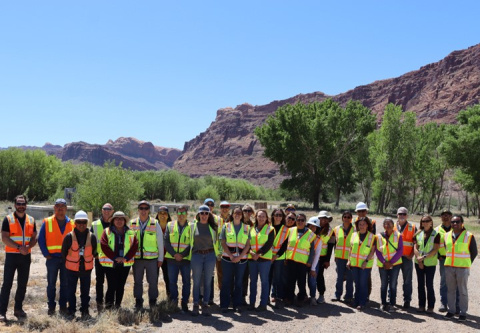A group of people in safety vests pose for a group photo at the Moab Site
