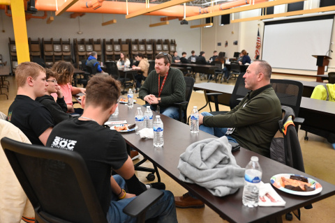 A group of students and professionals sitting at a table talking to each other