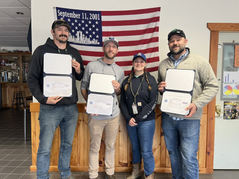 Four WVDP employees posing with certificates in an office