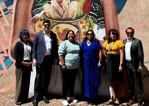 Group stands in front of mural