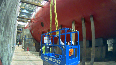 Employees in a blue lift working on a large red submarine at the Idaho Site