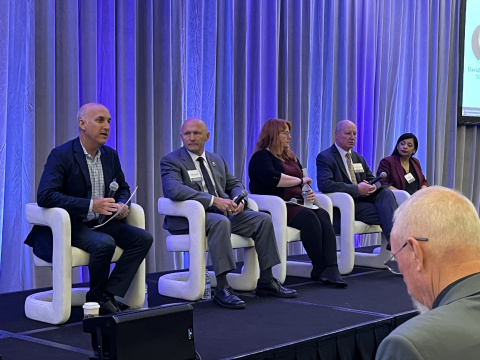 DOE Leadership and Officials sit on stage during a panel at a conference