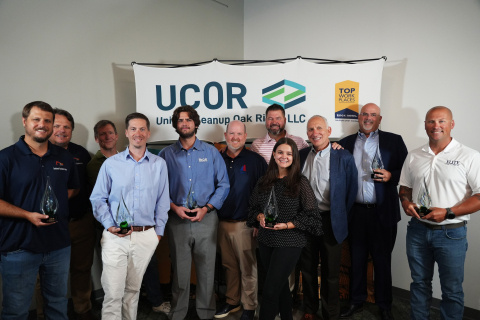 A group of professionals holding glass awards pose for a photo