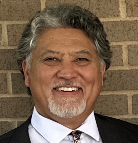 A headshot of a man in a suit smiling for a photo