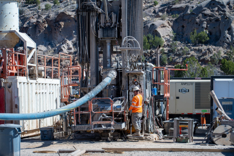 Crews in protective gear working on a large outdoor well at the Los Alamos site with a large blue tube coming out of it