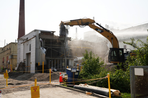 A large building being demolished with a crane and other construction vehicles