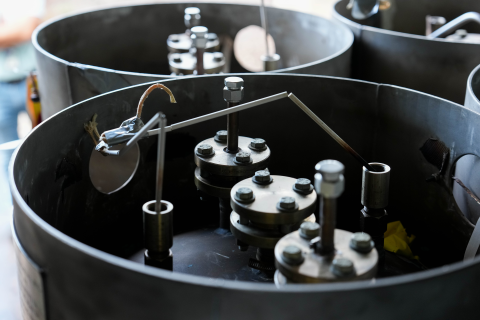 Close-up of FLiBe canisters delivered to Natura Resources, black metallic drums with valves on top.