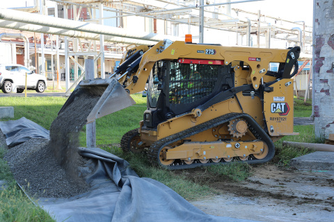 A yellow construction vehicle dumps gravel onto the ground at the Oak Ridge Site during a demolition