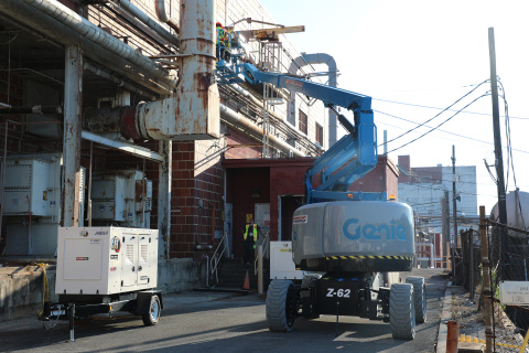 A blue construction crane conducting work on the side of a building