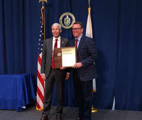 Two professionals holding an award posing for a photo together