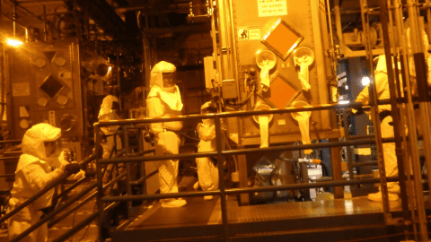 Rotating set of images of employees working in Hazmat suits in a facility building 