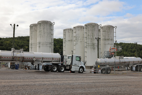 Large tanker trucks driving beside tall white towers at the Oak Ridge site