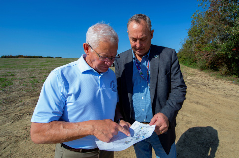 Two members of EM leadership stand outside at the Portsmouth Site and look at a piece of paper