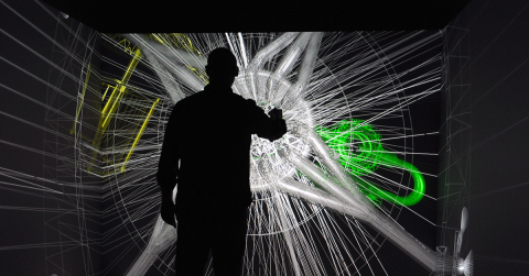 A researcher stands in front of a simulated computer modeling system