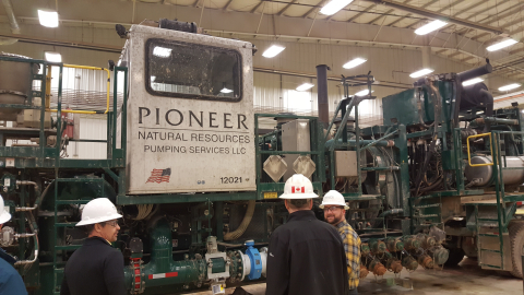 a photo of 3 men standing in from of a large PIONEER pump.