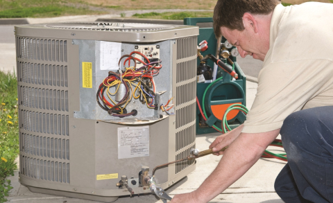 A technician installs central air conditioning equipment.