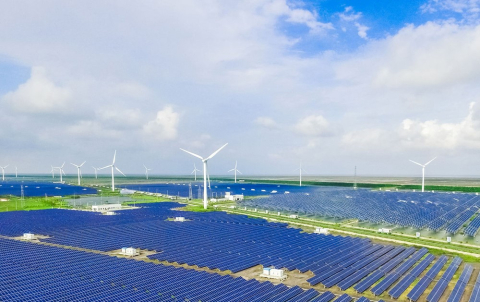 Photo of a field of solar panels and windmills.