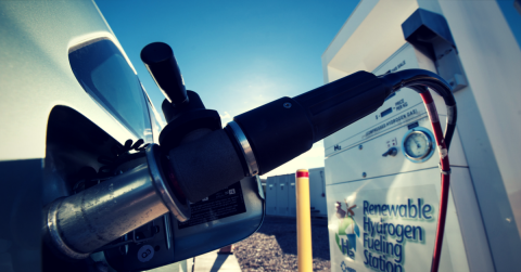Photo of a hydrogen station and a pump filling up a car.
