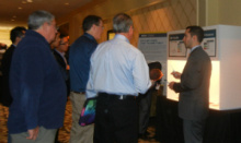 People standing in a display lobby talking to a man next to a display table.