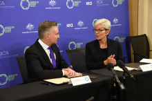 Australia's Minister for Climate Change and Energy, Chris Bowen, and U.S. Secretary of Energy, Jennifer Granholm, sit next to each other in front of a purple background behind a black table and discuss the joint statement with press in Australia.
