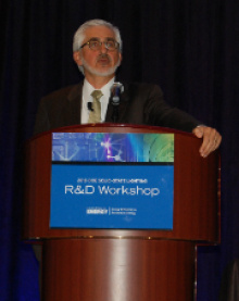 Man standing at a lectern addressing an audience.