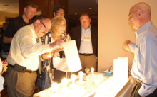People standing next to a display table looking at different types of lighting.