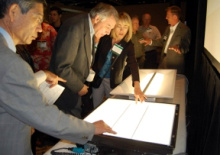 People in business attire standing over light tables looking at them.