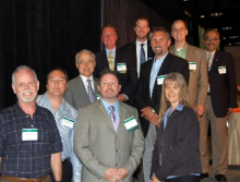 A group of men and women in business attire standing and facing the camera.