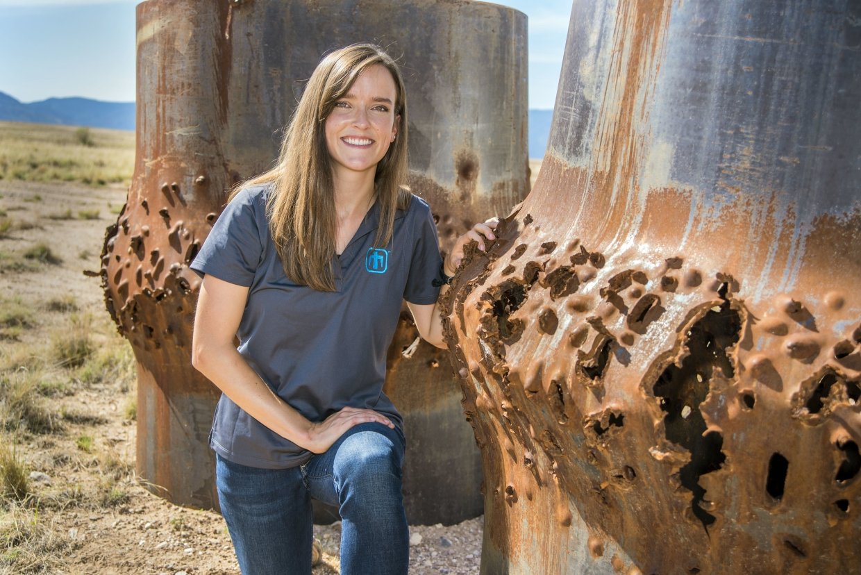 Rebecca Nylen kneels next to blasted steel cylinders, some of her handy work as a computational shock physicist.