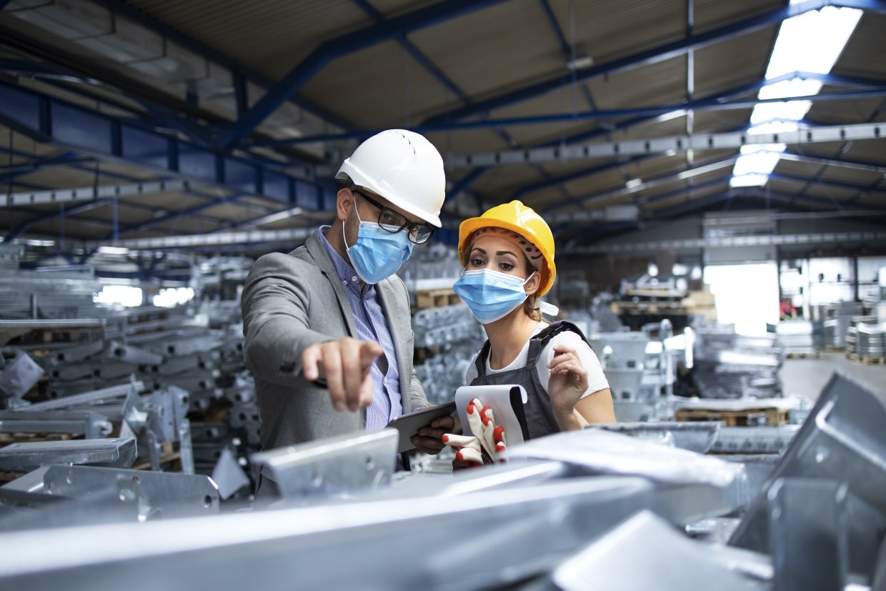 2 workers wearing masks in a manufacturing plant
