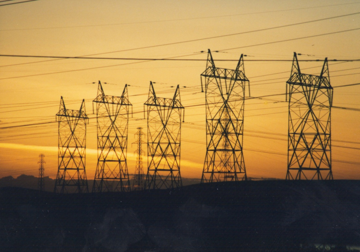 A row of power lines on the horizon, with the sky beyond in the midst of a setting sun.