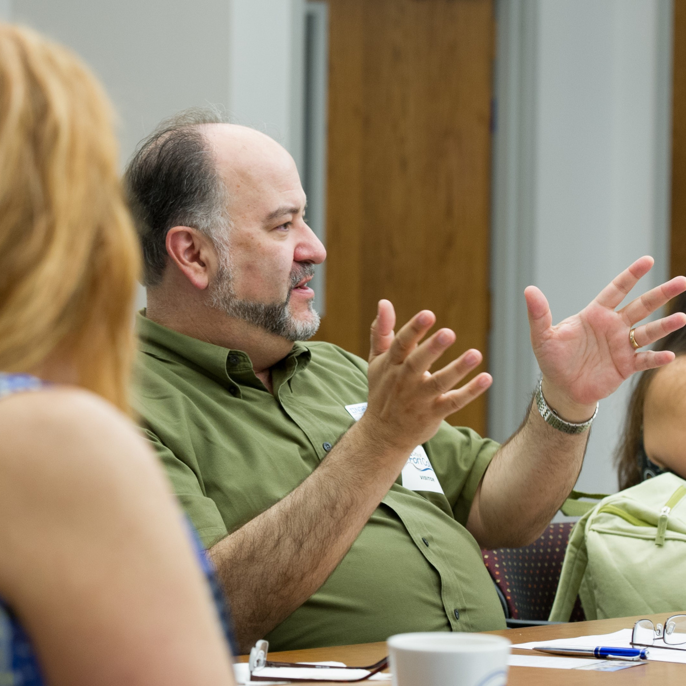 Photo of people at a conference table and a man talking.