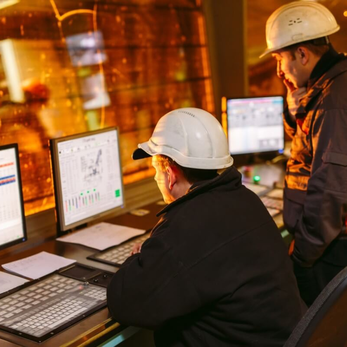 Two men in hardhats looking at data on a computer.