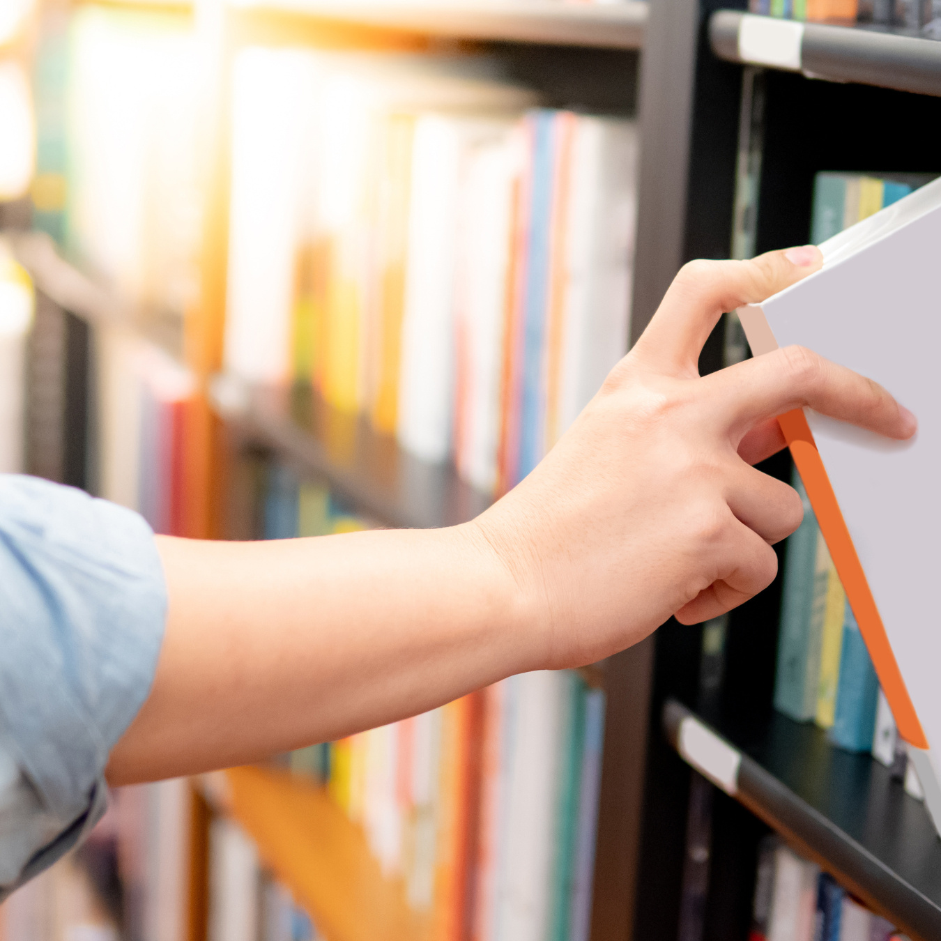View of the arm of a person putting a book on a bookshelf.