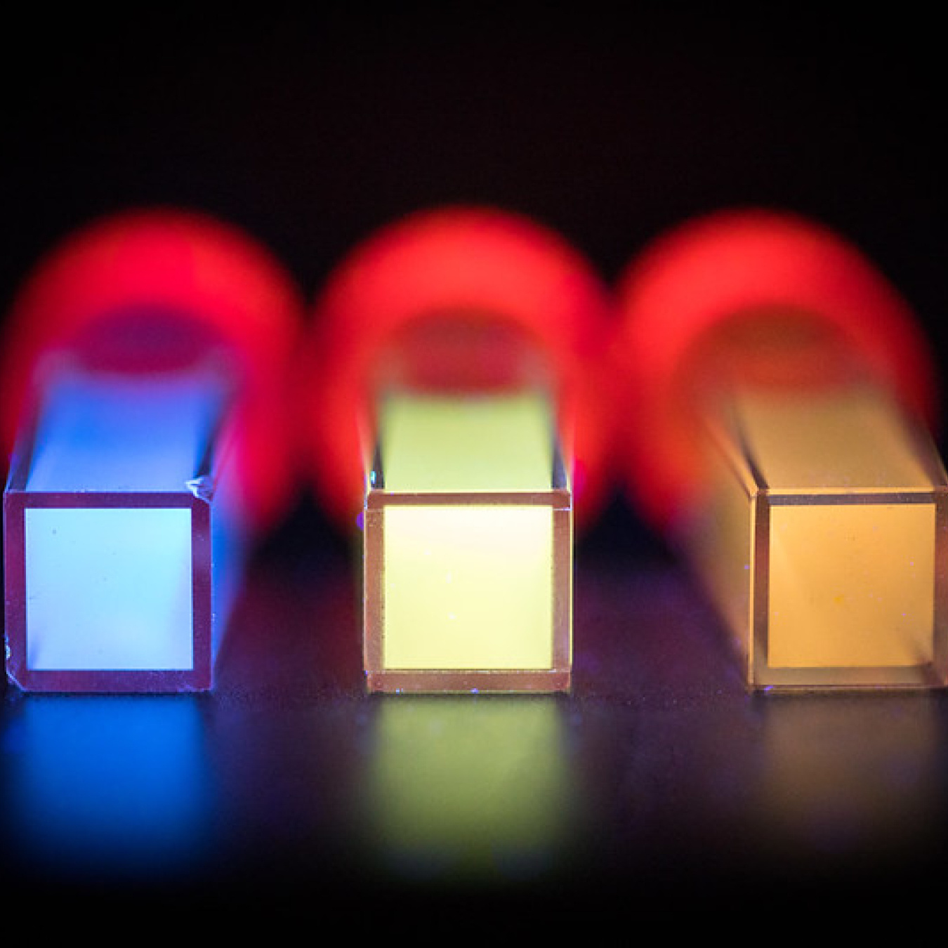Three tubes lay on a black surface with brightly colored materials inside