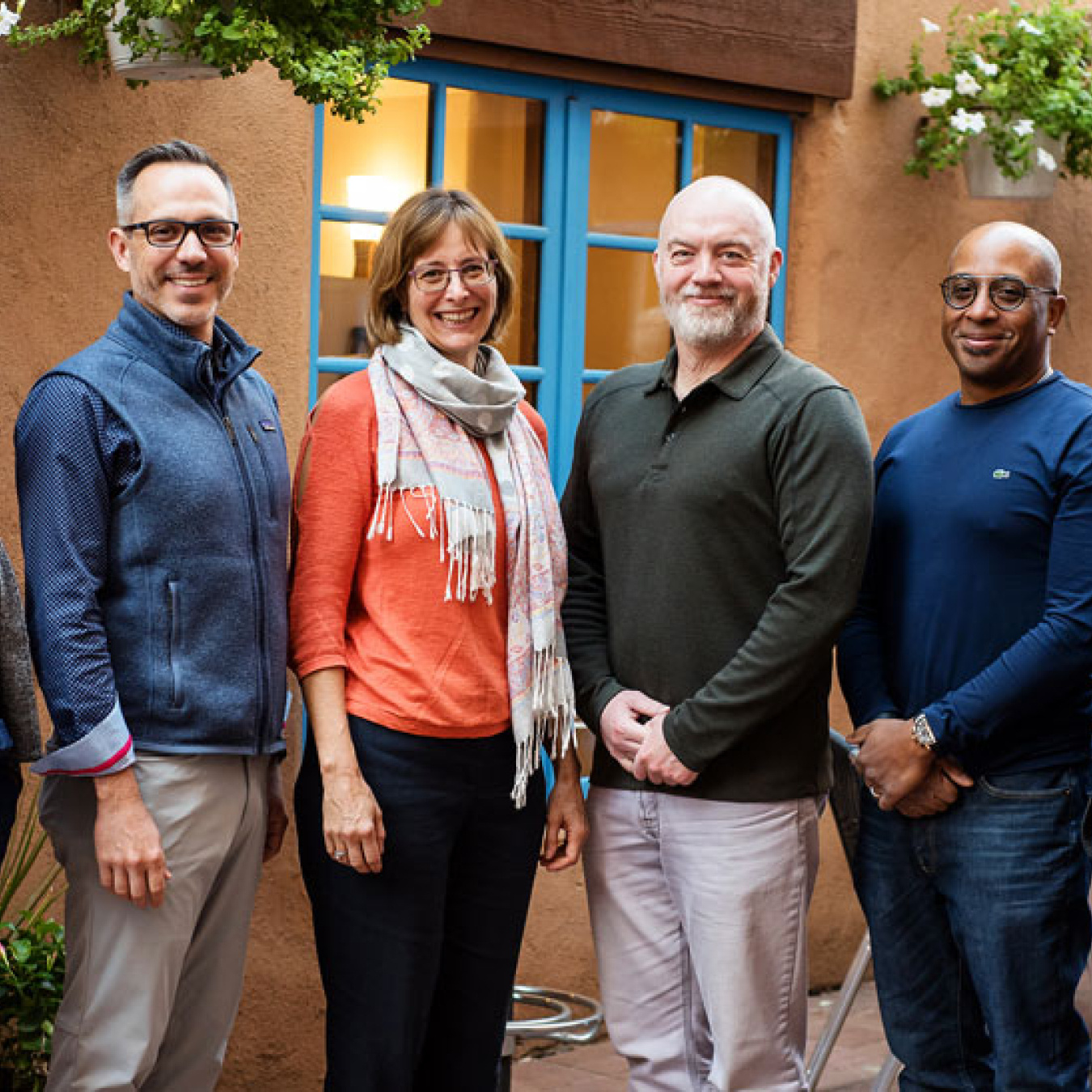 A group of six people stand together for a photo on an outdoor patio.