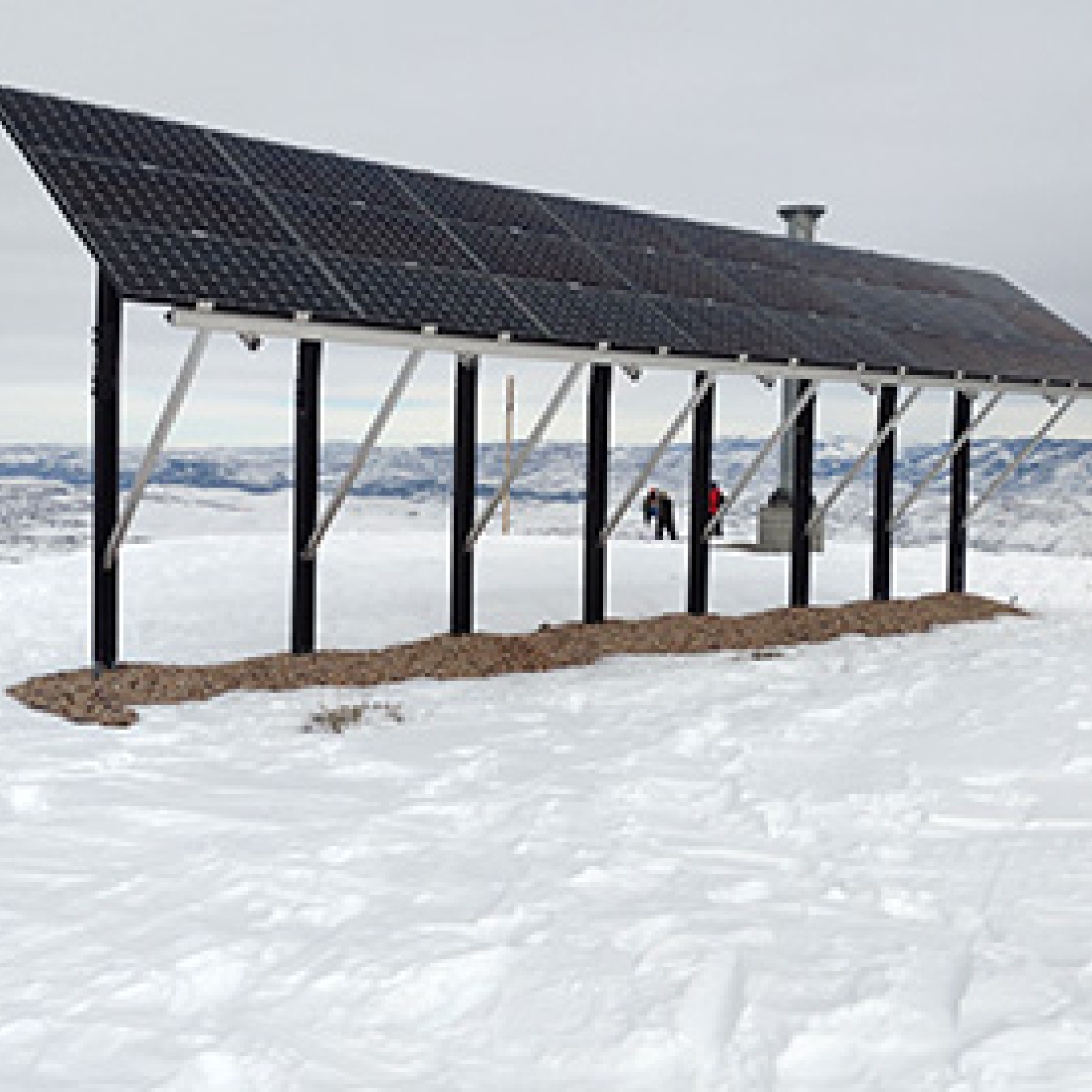 A solar array in the mountains surrounded by snow.