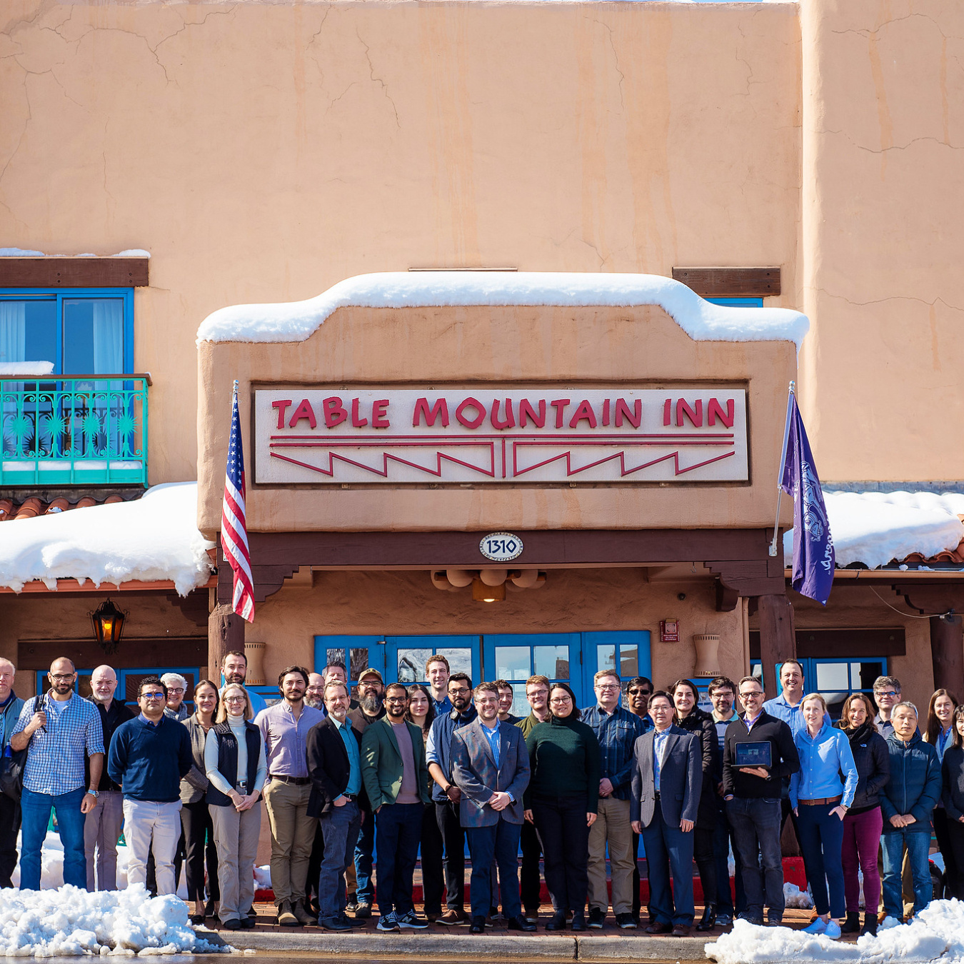 A group of 40 people stand and pose in front of a building.