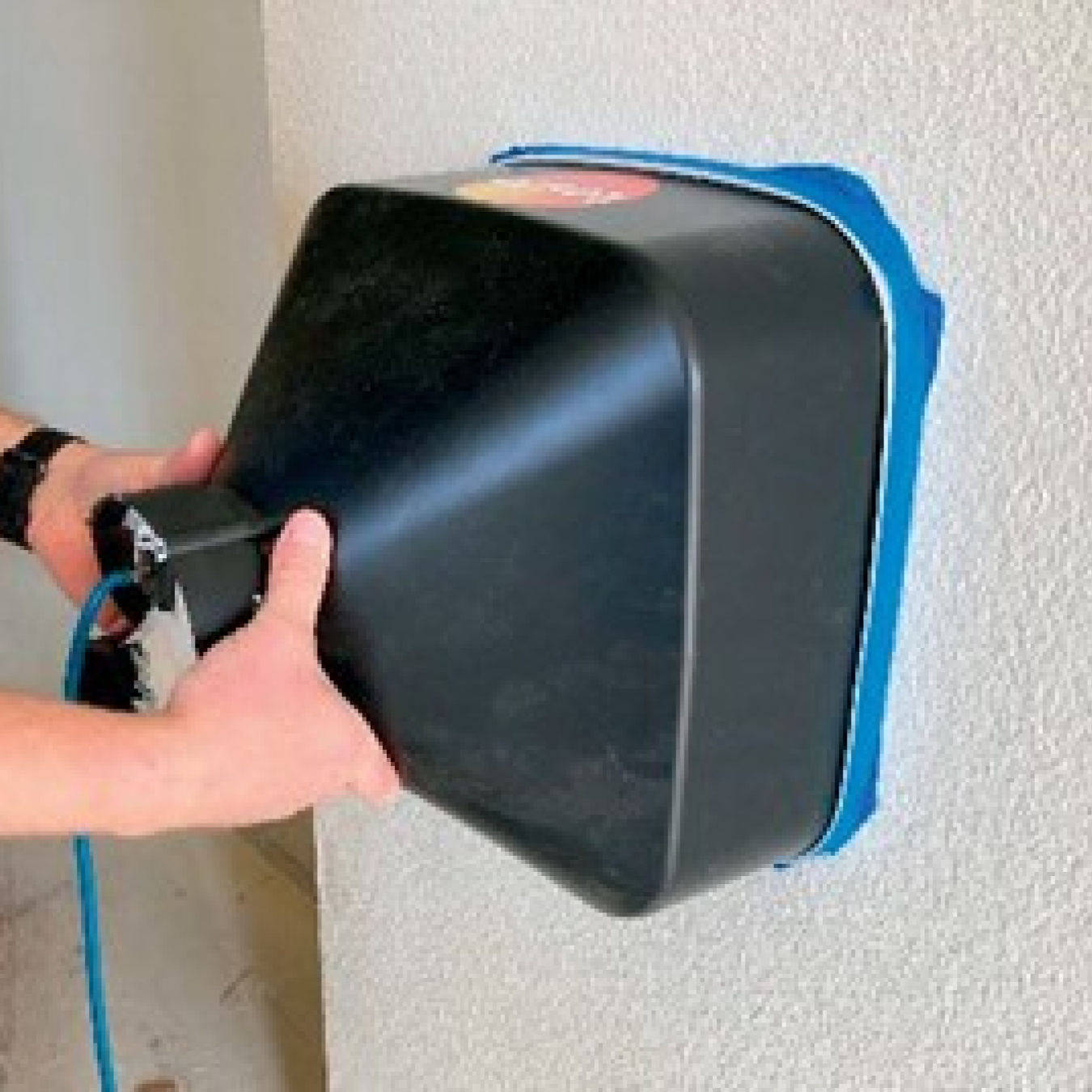 Person holds machine up to wall inside house to measure air flow