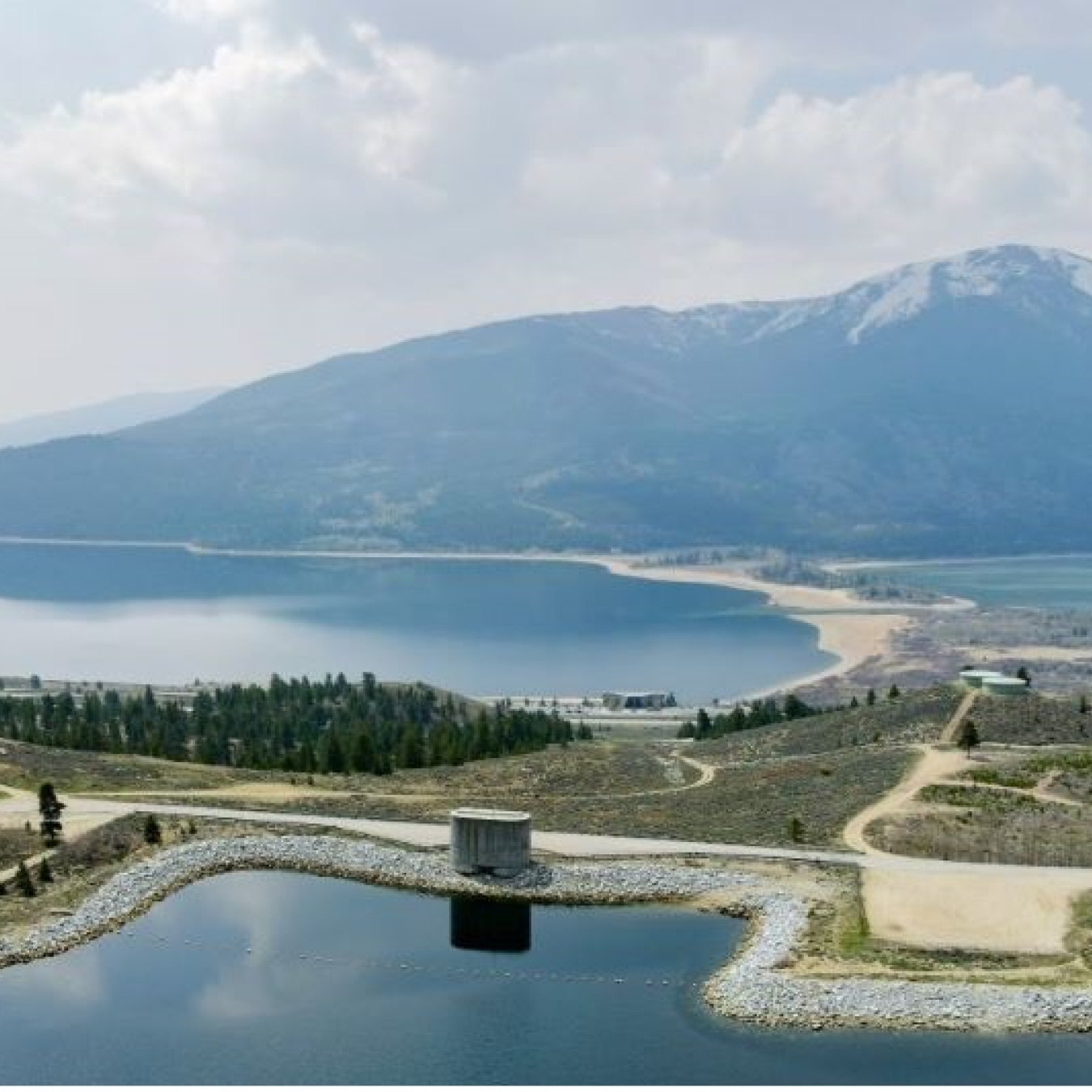 Aerial view of the Mount Elbert pumped storage hydropower facility in Lake County, Colorado, on the shore of Twin Lakes with mountains in the background.