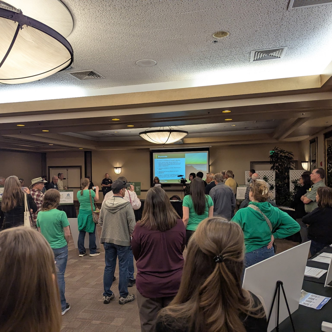 A group of people in a room face the front of the room where a presentation is being given
