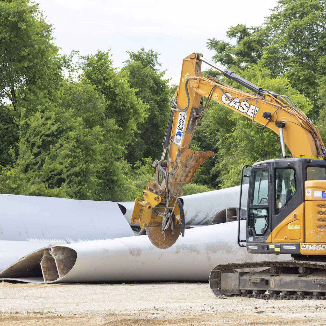 A bulldozer moves past wind turbine blades on the ground.
