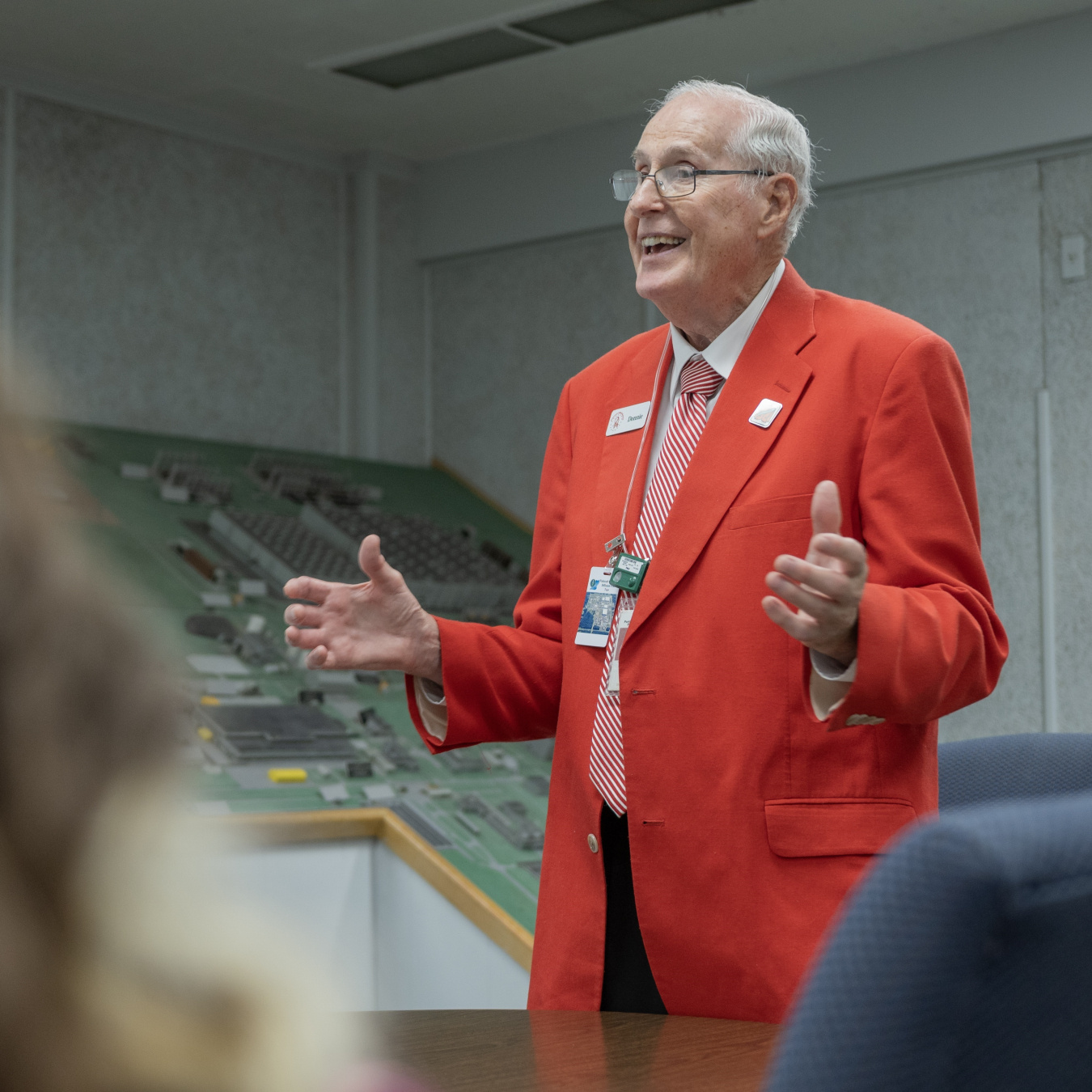 A man in an orange suit giving a tour to a group of people