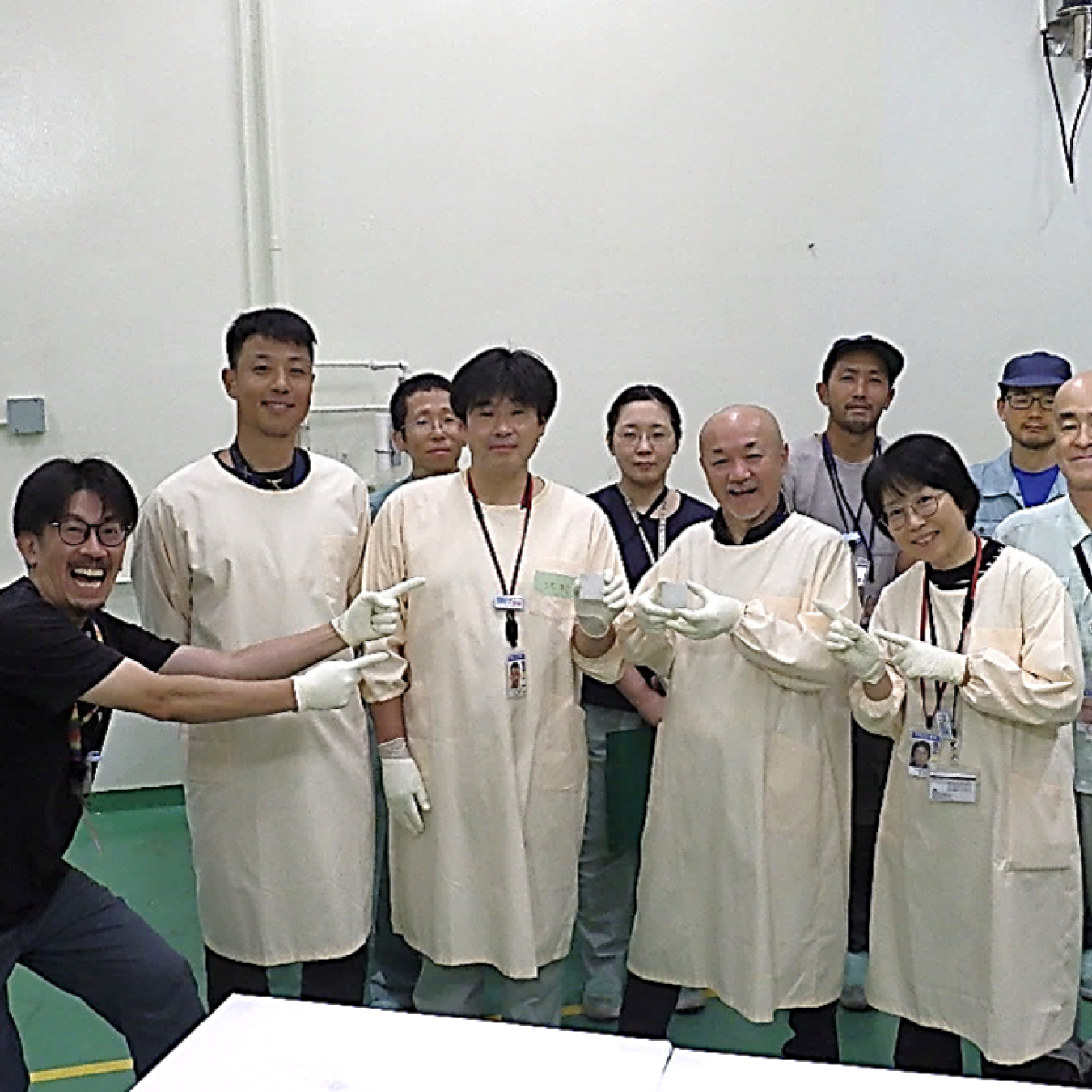 A man points to a group of nine people with an excited expression on his face and points to the group.