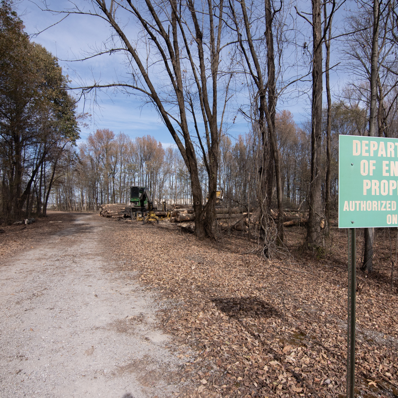 A road lined with trees with a green sign that reads "Department of Energy Property"