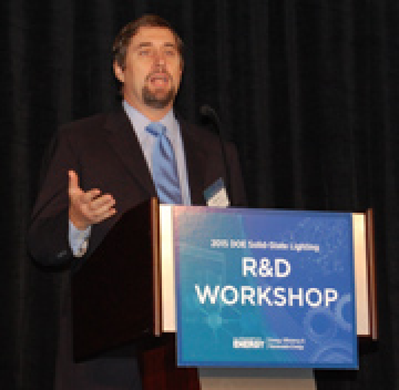 Man standing at a lectern, addressing the conference audience.