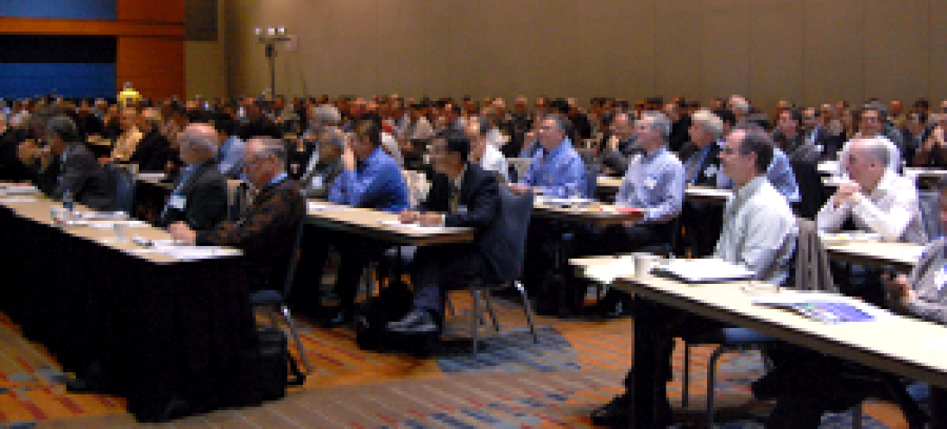 Photo of a group of people assembled in a meeting room, listening to a speaker.