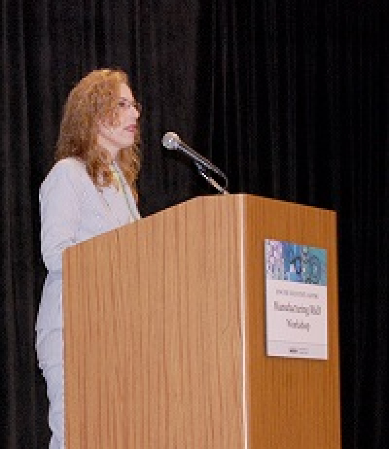 Woman speaking at a lectern at an event, addressing the audience.