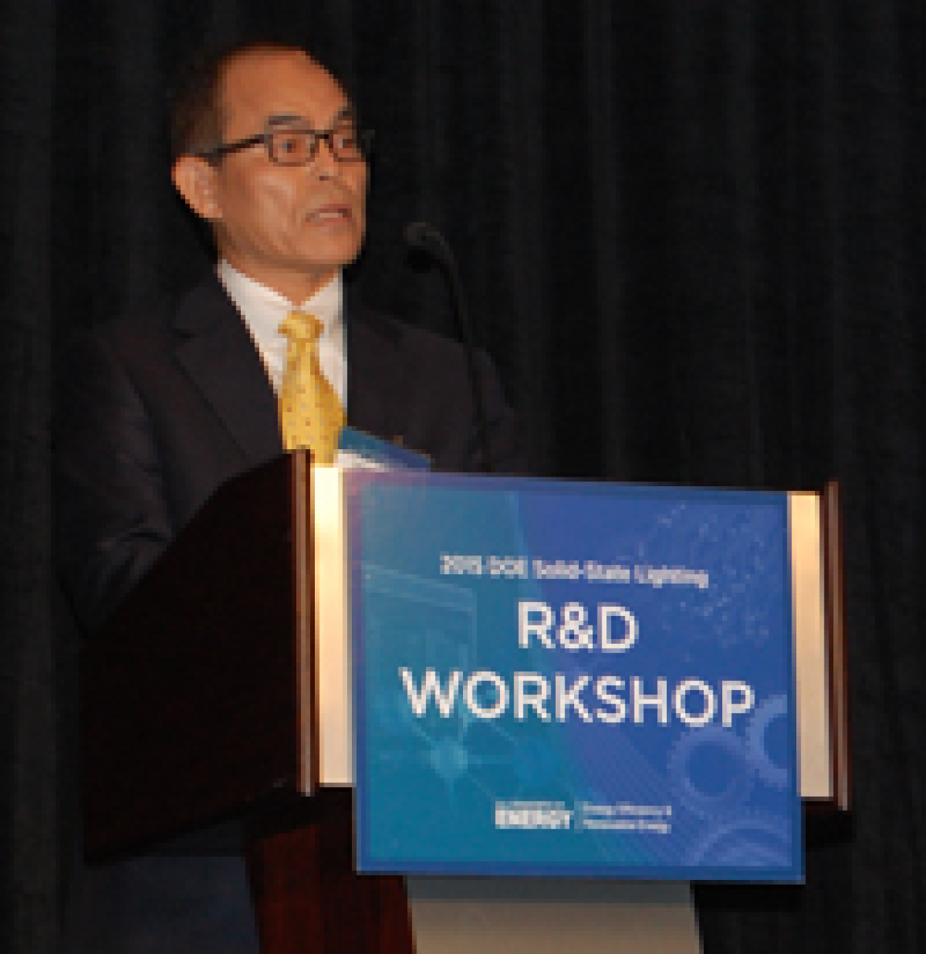 Man standing at a lectern, addressing the conference audience.