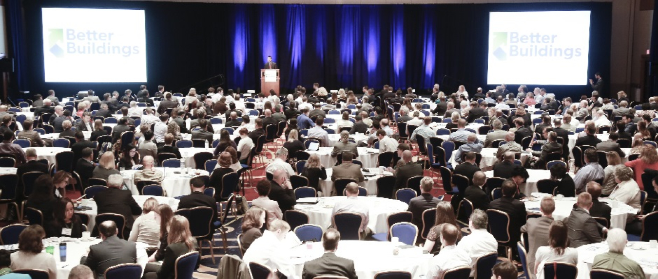 Large group of people in a convention hall or auditorium watching a presentation.